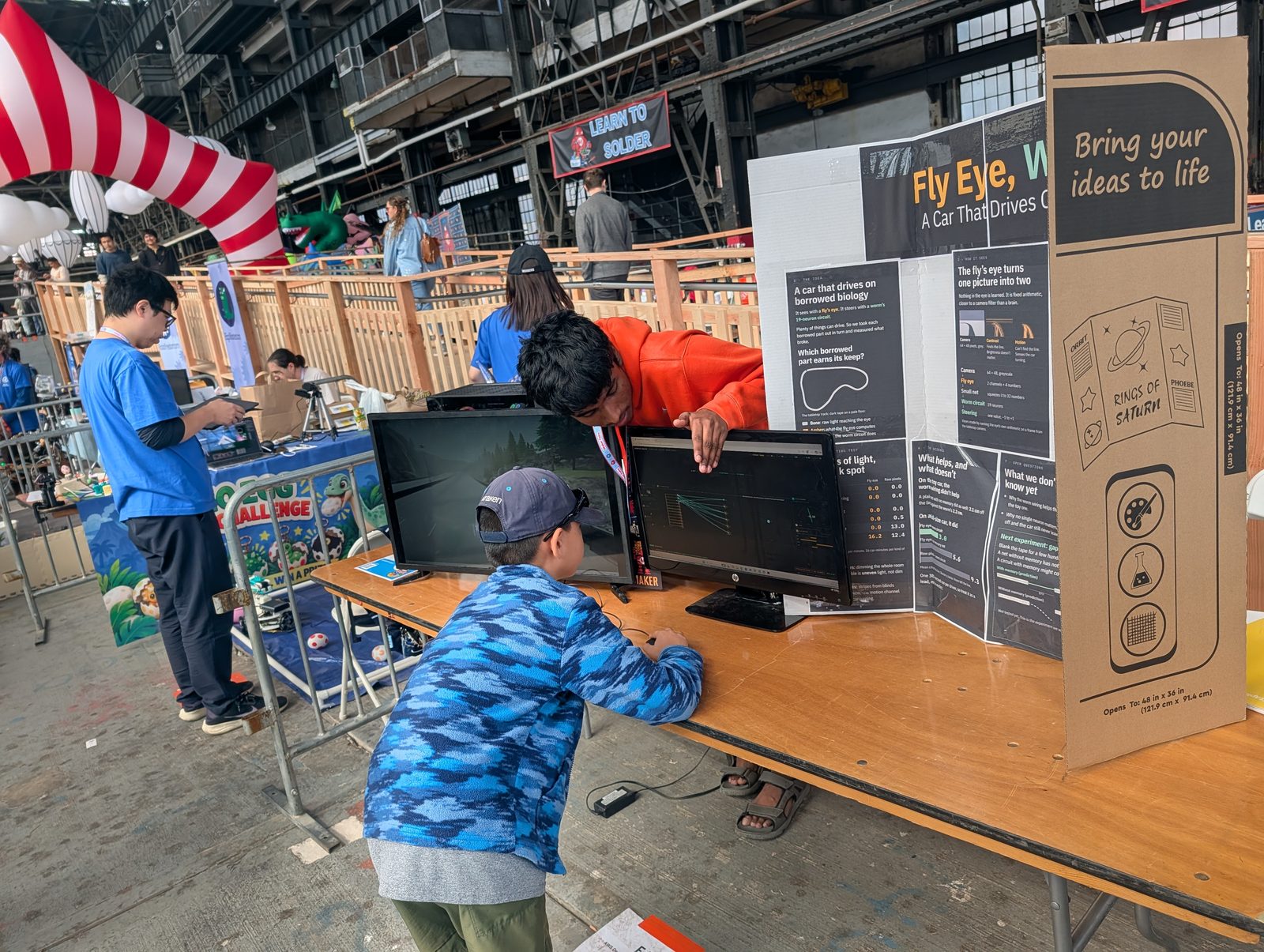 A young visitor explores the neuron display while the exhibitor explains the circuit